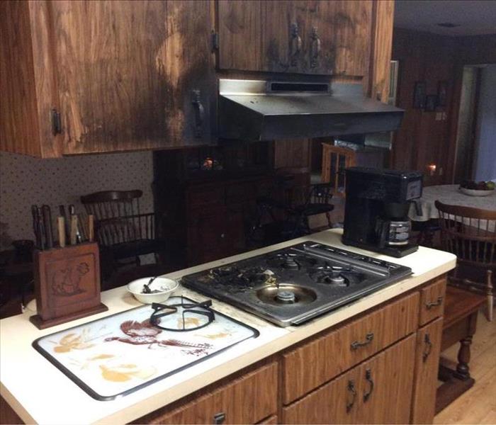 Kitchen cabinets, stove top, and range hood all affected by smoke and soot